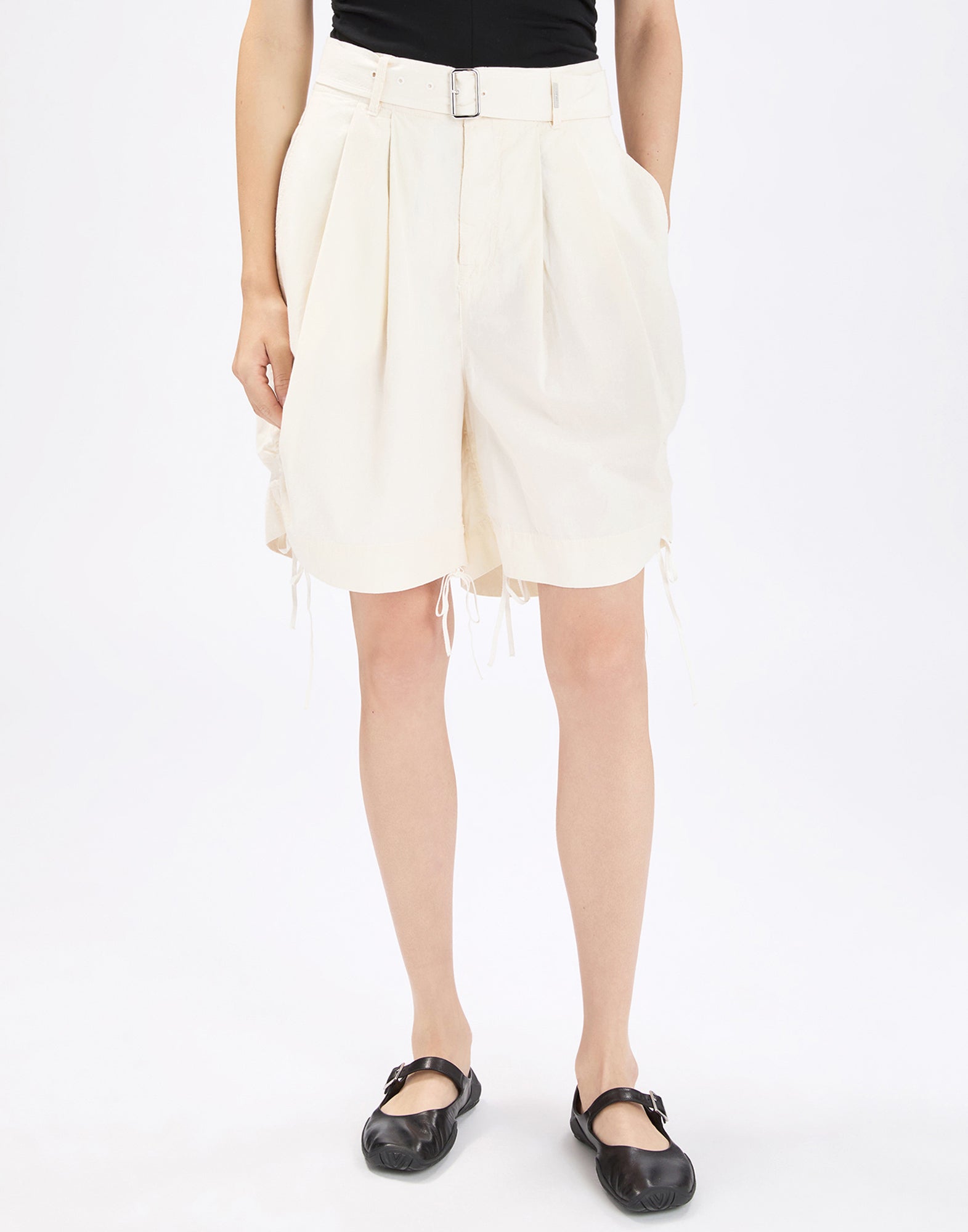 Front view: person wearing wide-cut, cream ORDER Bermuda shorts in cotton poplin with pleats at the waist, integrated belt with metal buckle, side pockets, and adjustable drawstrings at the hem.