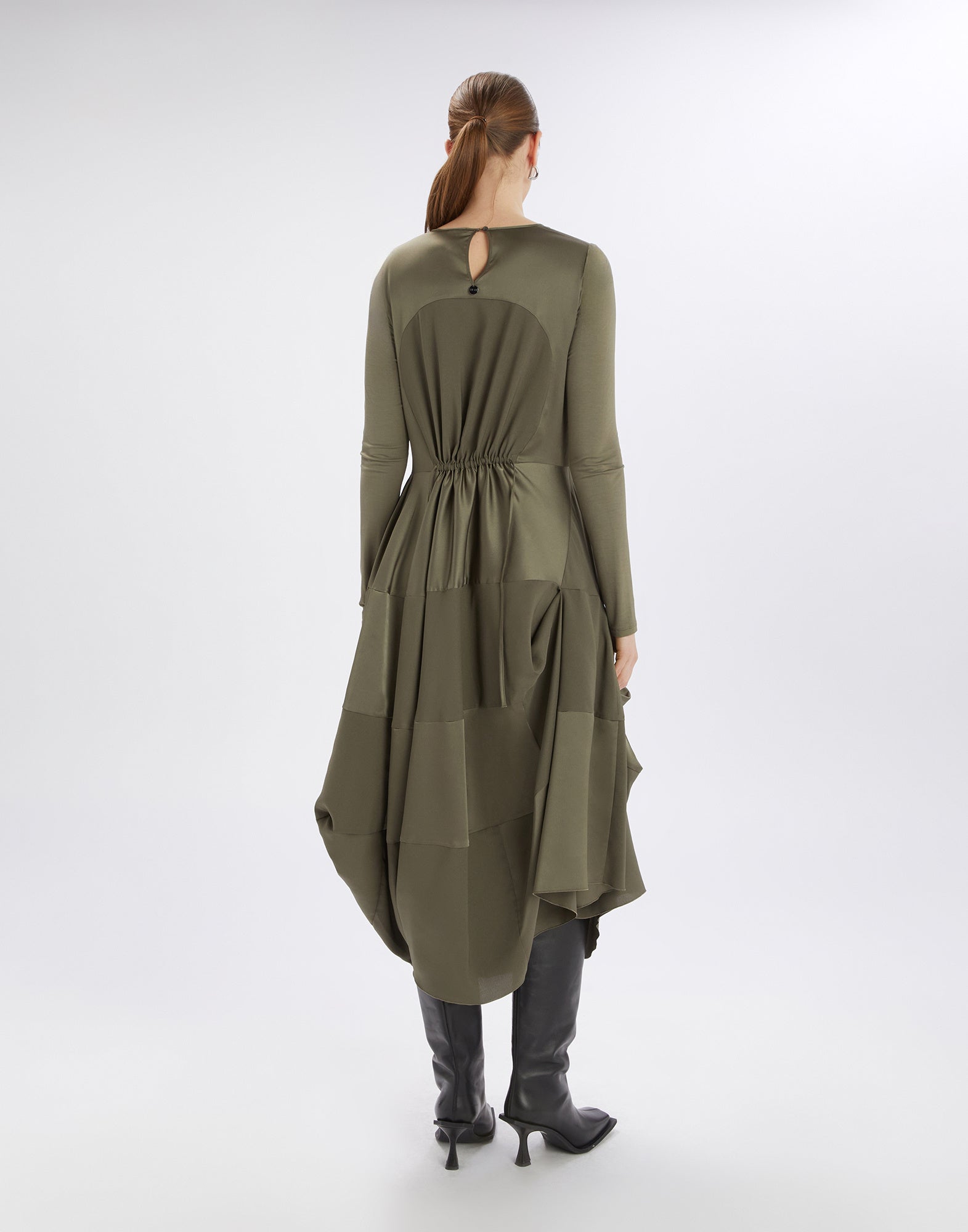 Back view of the PLACID dress in olive green, featuring long sleeves, keyhole opening at the back, and draped, flowing satin fabric on the lower jersey section.